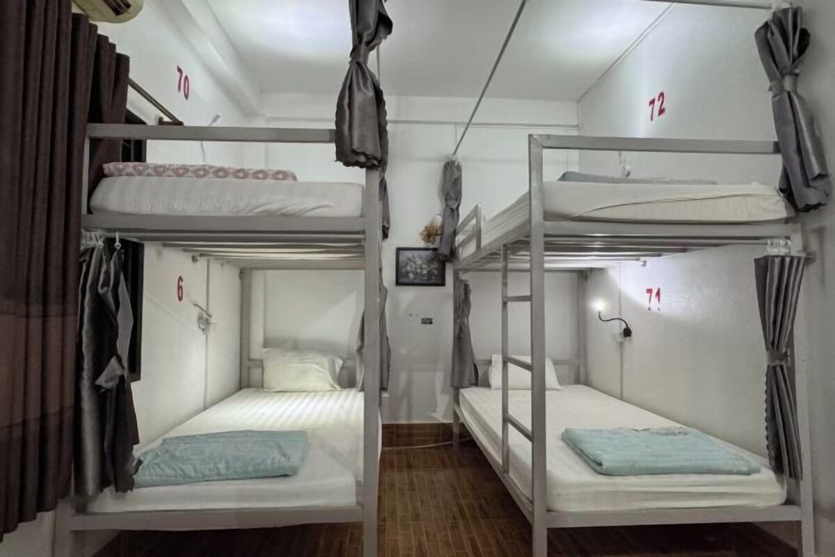 Une chambre de dortoir avec des lits superposés, des lits numérotés et des rideaux.