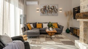 A modern living room with a grey sofa, a wooden coffee table, and a painting of elephants on the wall. - Villa Katarina with pool (Zadar)