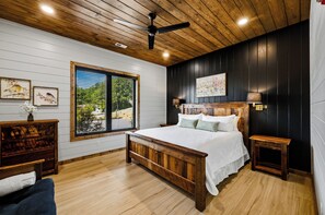 A bedroom with a wooden bed, a window with blinds, a ceiling fan, and a painting on the wall.