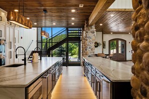 A modern kitchen with a central island, a stone accent wall, and a view of the outdoors.