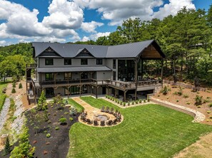 A two-story house with a balcony, a deck, and a circular fire pit area.