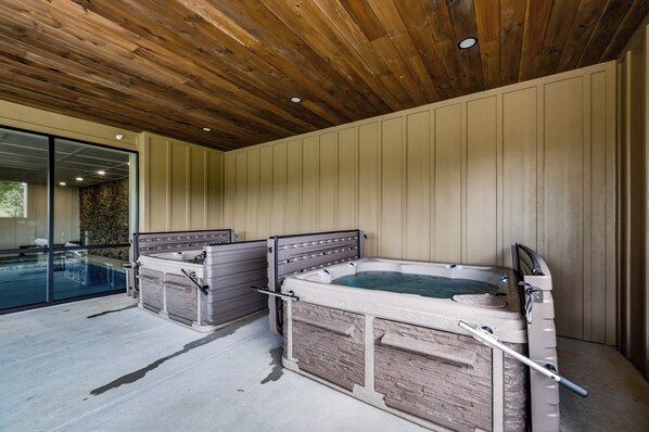 Un área de spa con dos jacuzzis y una piscina cubierta con paredes de vidrio.
