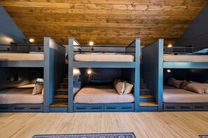 Habitación con literas, techo de madera y pared azul.