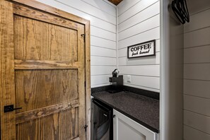 A kitchen with a wooden door, a coffee sign, and a countertop.