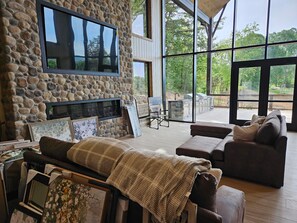 Una chimenea de piedra, un televisor grande y una zona de estar acogedora con vistas al exterior.