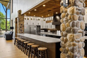 Una cocina moderna con pared de piedra decorativa, techo de madera y una zona de bar con taburetes.
