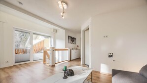 A spacious room with a large window, a marble table, and a grey sofa. - Apartment in Hotting Near Nordkette (Innsbruck)
