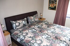 Un letto con biancheria da fiori, un comodino con una lampada e un quadro appeso al muro.