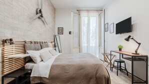 A modern bedroom with a large bed, a desk, and a TV.