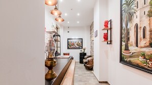 A hallway with a wooden bench, a brass lamp, a framed painting, and a decorative wall piece.