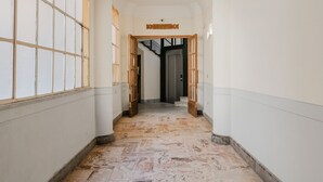 A hallway with a marble floor, wooden doors, and a sign reading "SALA E".
