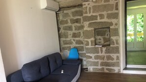 Une pièce avec un mur en pierre, une chaise bleue et un canapé gris.