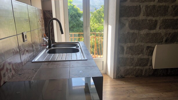 Une cuisine au design moderne, dotée d’un grand évier, d’un crédence ornée de carreaux à motifs et offrant une vue sur la verdure grâce à une fenêtre.