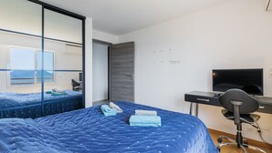 A modern bedroom with a large bed, a desk with a computer, and a TV. - Apt MEDICIS – Sea View, Terrace & Pool (Mandelieu-la-Napoule)