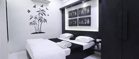 A modern bedroom with a bed, a wall-mounted air conditioner, and a nightstand.