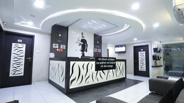 A modern reception area with a reception desk, seating area, and glass walls. - Hotel Paramount Inn (Rajkot)