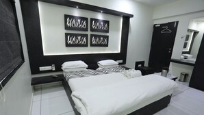 A modern bedroom with a large bed, bedside tables, a wall-mounted TV, and a wardrobe. - Hotel Paramount Inn (Rajkot)