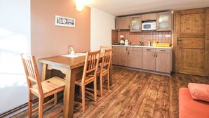 A compact kitchen with wooden cabinets, a microwave, and a dining area with a wooden table and chairs. - Lovely apartment in villa for 4 guests with pool, WIFI, TV and pets allowed (Prachatice)