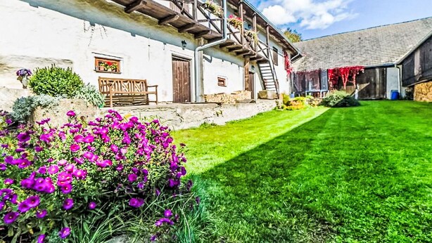 A traditional white building with a wooden balcony, a bench, and a well-maintained lawn. - Lovely apartment in villa for 4 guests with pool, WIFI, TV and pets allowed (Prachatice)