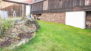 A rustic barn with a stone wall and a grassy yard.