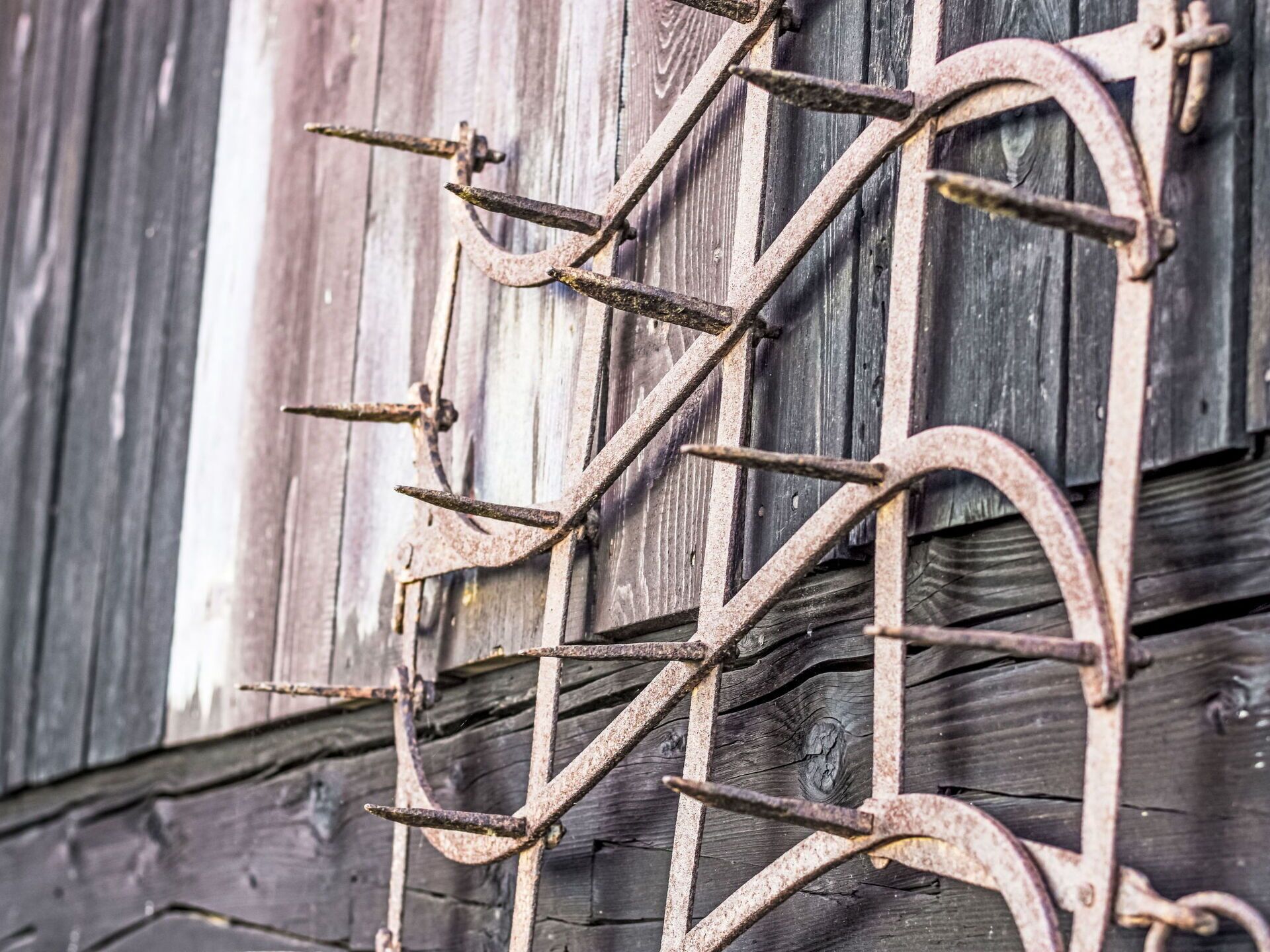 Une porte en métal rustique, fixée à un mur en bois.