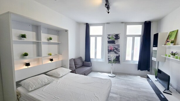 Un dormitorio moderno con cama, estanterías empotradas, un escritorio y un ventanal grande.