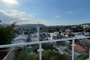 Paisagem urbana com mistura de edifícios modernos e tradicionais, uma torre branca imponente e céu claro.