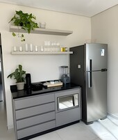 Cozinha moderna com frigorífico embutido, bancada com liquidificador e uma planta em vaso.