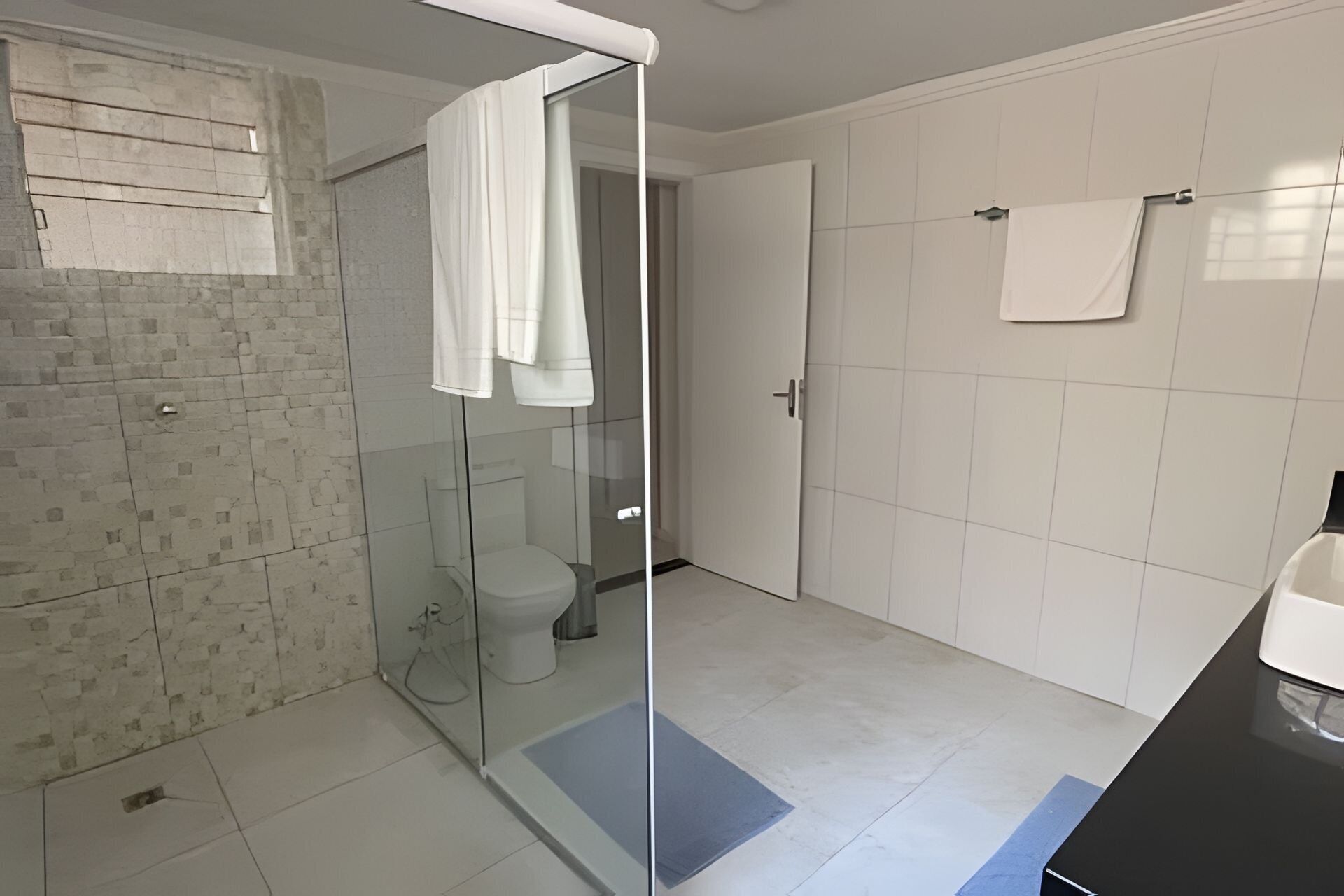 A modern bathroom with a glass shower enclosure, a toilet, and a sink.