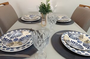 Uma mesa de jantar posta com pratos, copos e um vaso de flores.