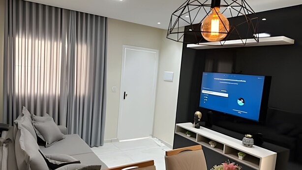 Un saló modern amb un sofà, un televisor i una lluminària decorativa.