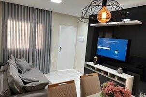 Uma sala de estar moderna com um sofá, uma TV e um lustre decorativo.