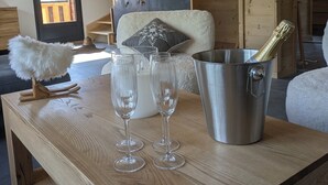 A wooden table with three wine glasses and a champagne bucket in a modern interior with wooden beams and a mountain view. - Modern chalet La Tanière with sauna in Le Chinaillon (Le Grand-Bornand)