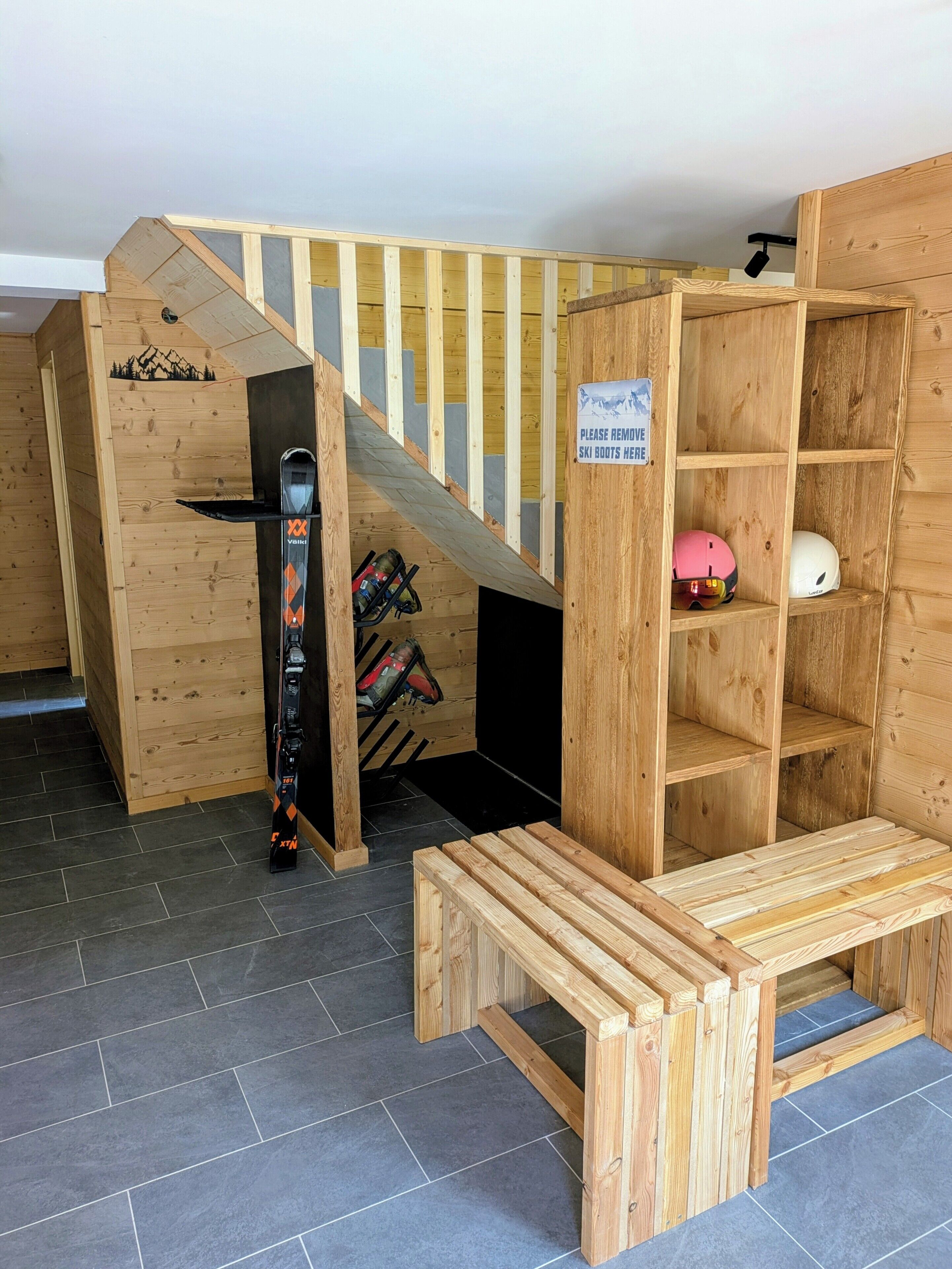 A wooden ski boot storage area with a sign instructing to remove ski boots.
