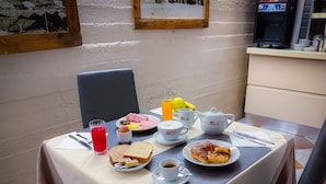A breakfast table with various food items, a teapot, cups, and a juice dispenser. - B&B Villa Le Farnete (Comeana)