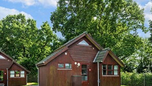 Een houten chalet met een puntdak, een klein terras en een bord met het cijfer '20'.