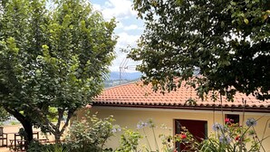 A building with a tiled roof, surrounded by lush greenery and flowering plants.