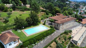 Una amplia piscina rodeada de césped cuidado y árboles, con edificios de piedra en las cercanías.