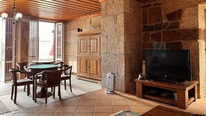 Una habitación con techo de madera, paredes de piedra, una mesa de billar y un televisor sobre un atril de madera.