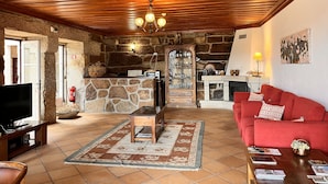 A cozy living room with a stone fireplace, wooden ceiling, and a red sofa.