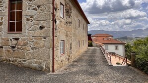 A stone building with a cobblestone path leading to a white building with a red roof.