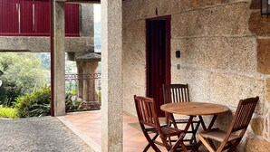 A stone building with a red door, a round wooden table with four chairs, and a stone balustrade. - Nomad s Country - Cimo de Vila The Granary View (Cabeceiras de Basto)