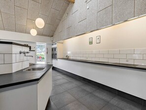 Een moderne keuken met witte kasten, een zwart aanrecht en een groot eiland. Er zijn twee hanglampen en een roestvrijstalen spoelbak.