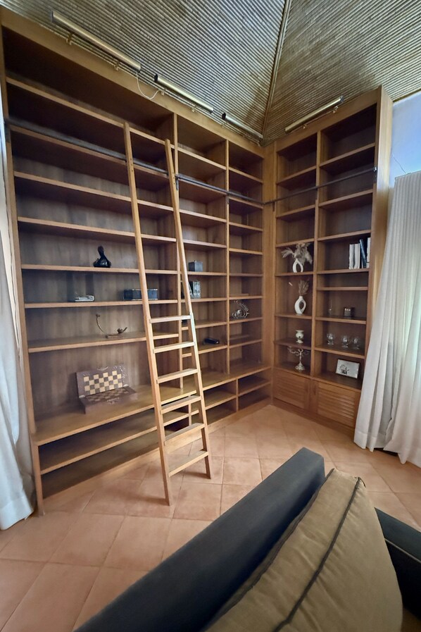 Une pièce avec une grande bibliothèque en bois, une échelle et un banc rembourré.