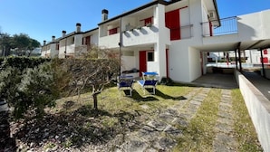 En moderne boligbygning i to etager med fladt tag, hvide ydervægge og røde detaljer.