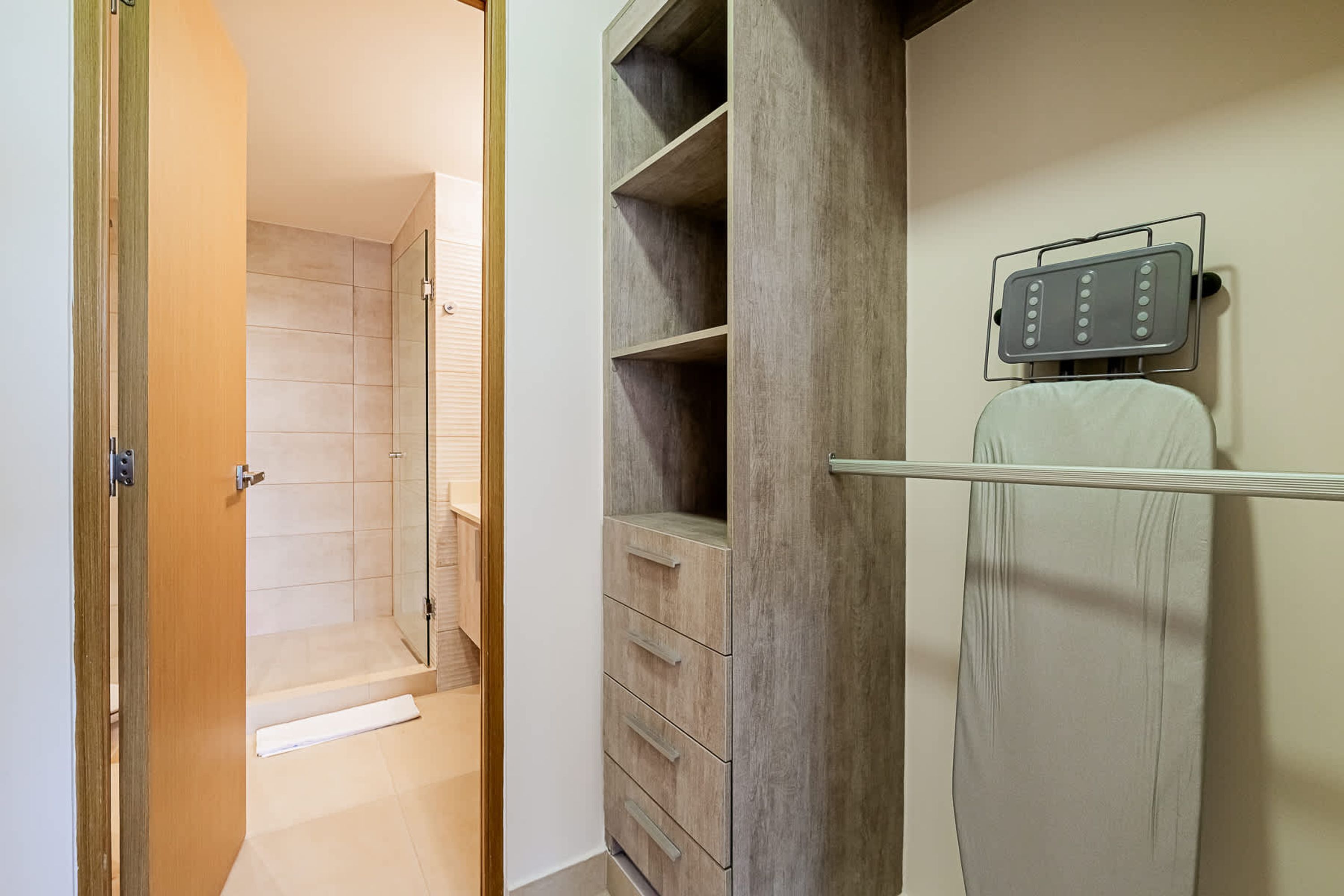 Un baño con ducha, tocador de madera con cajones y un perchero para toallas.