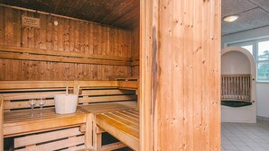 A wooden sauna with benches and a bench table, a sign on the wall, and a window in the background. - 4 Person Holiday Park Home in Romo (Rømø)