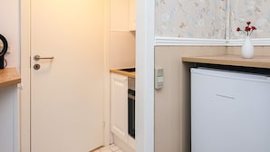A compact kitchen with a white refrigerator, a wooden countertop, and a white door. - 4 Person Holiday Park Home in Romo (Rømø)
