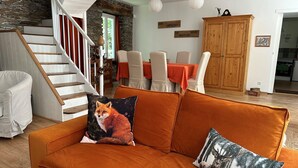 A living room with a staircase, orange sofa, and a fox-themed pillow. - Cottage by River With Spa Near Carcassonne (Caudebronde)