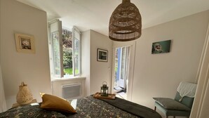 A bedroom with a bed, a window, a chair, and a hanging light fixture. - Cottage by River With Spa Near Carcassonne (Caudebronde)